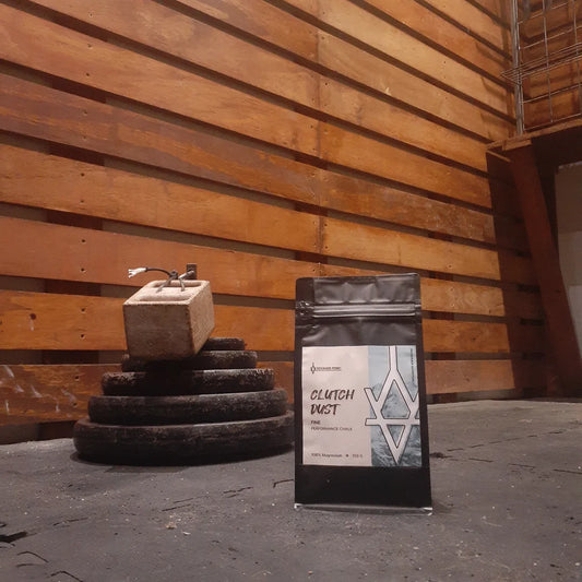 rock climbing chalk bag labeled 'Clutch Dust' in front of a wooden wall.
